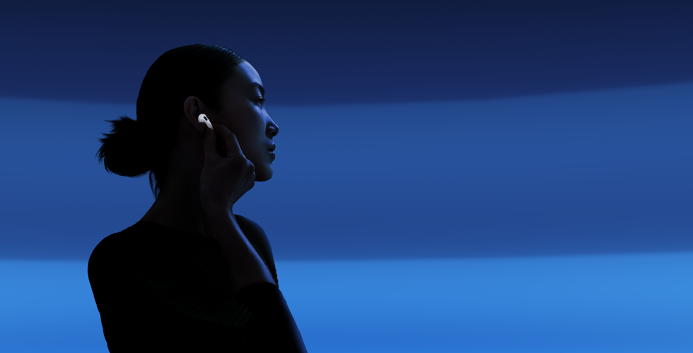 親指と人差し指でAirPods 5の軸部分をつまみ、リスニングモードを切り替えている人物