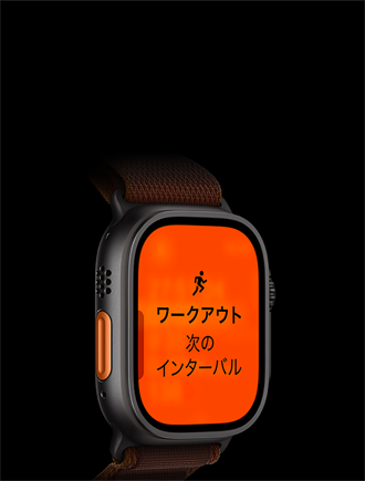 ブラックチタニウムケースのApple Watch Ultra 4。ランニングワークアウトで「次のインターバル」と表示されている。左側面の外観、オレンジのアクションボタン。アルパインループバンド