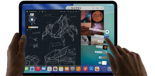 iPad Pro、カラーはスペースブラック、左手でデバイスを持ち、右手で複数の開いているアプリのウインドウを指差して操作するジェスチャーをしている。描画アプリと機械設計のスケッチ、惑星や宇宙の画像が保存された写真ライブラリ、扇状に広がったダウンロードフォルダ内のファイル