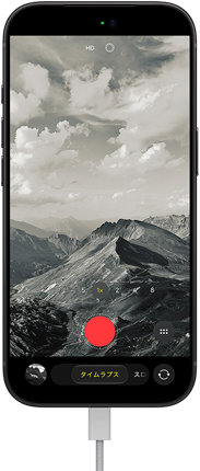 iPhone 18 Proの前面の外観。山脈の風景が表示されており、タイムラプスモードに設定されたカメラモードが重ねられている。充電ポートに電源ケーブルが接続されている