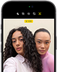 ブラックのiPhone 18 Pro、前面の外観。カメラに向かってポーズをとる2人のモデルが表示され、センターフレームフロントカメラの機能を示している